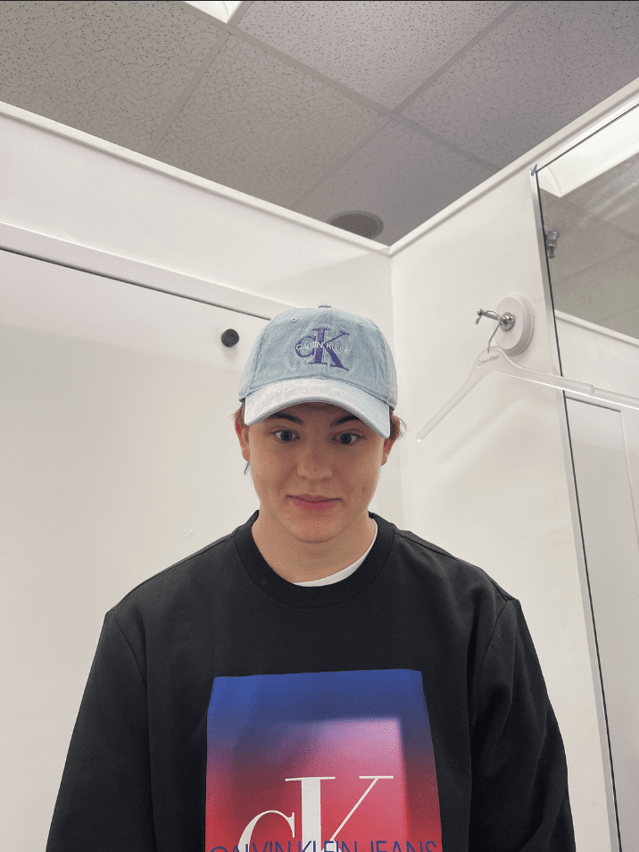 A young adult wears a Calvin Klein hat