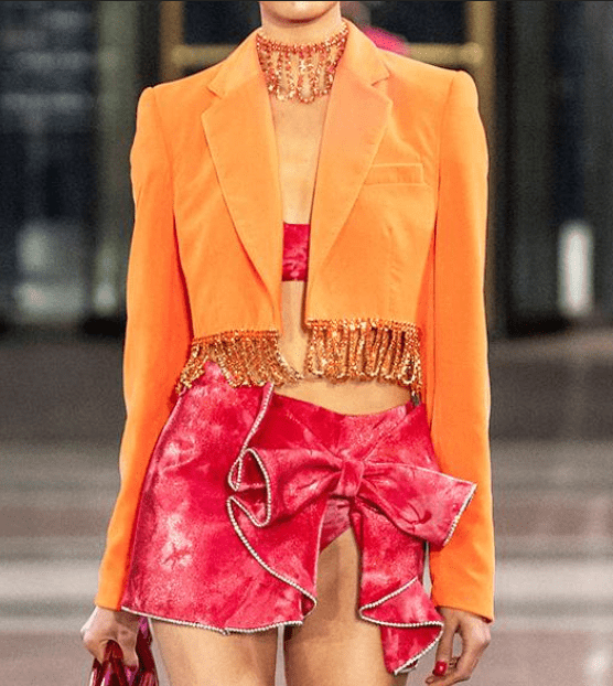 A woman wearing an orange blazer and a pink swimsuit