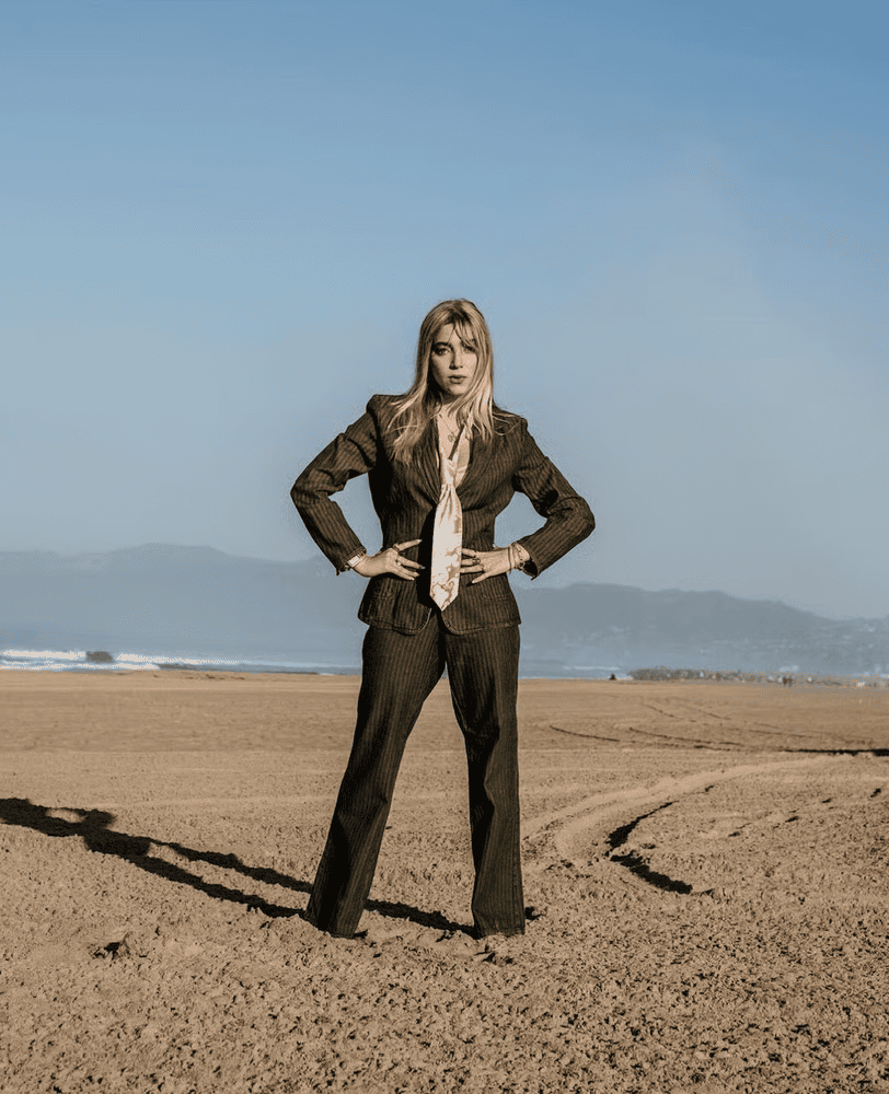Lexy Silverstein poses on a beach in a vintage-inspired tailored suit, showcasing sustainable fashion, personal style and her approach to making fashion more intentional.
